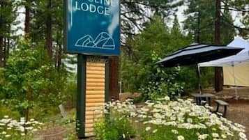 Skilt for The Incline Lodge med et bjergmotiv, omgivet af en have med hvide blomster og sten.