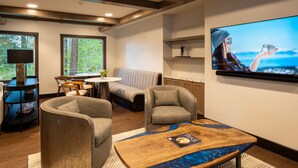 A modern living room with a sofa, armchairs, a coffee table, and a television mounted on the wall.