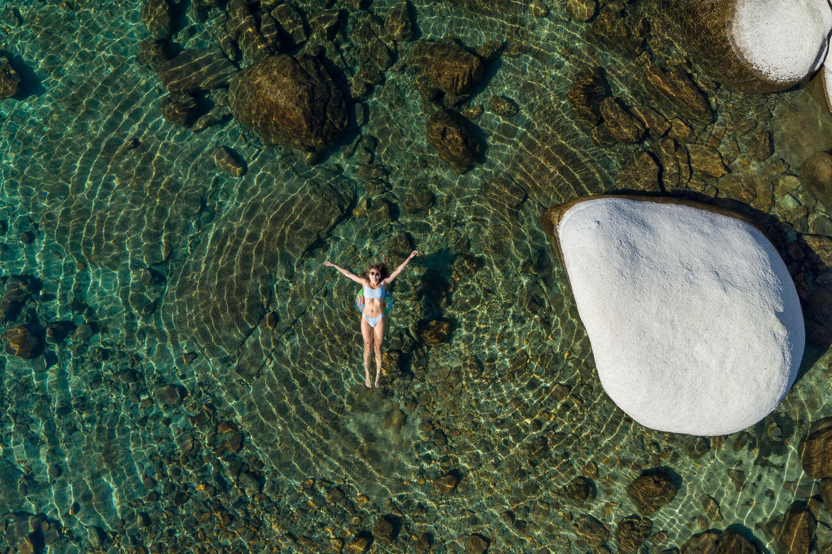 A person standing on a rocky surface with clear water around them.