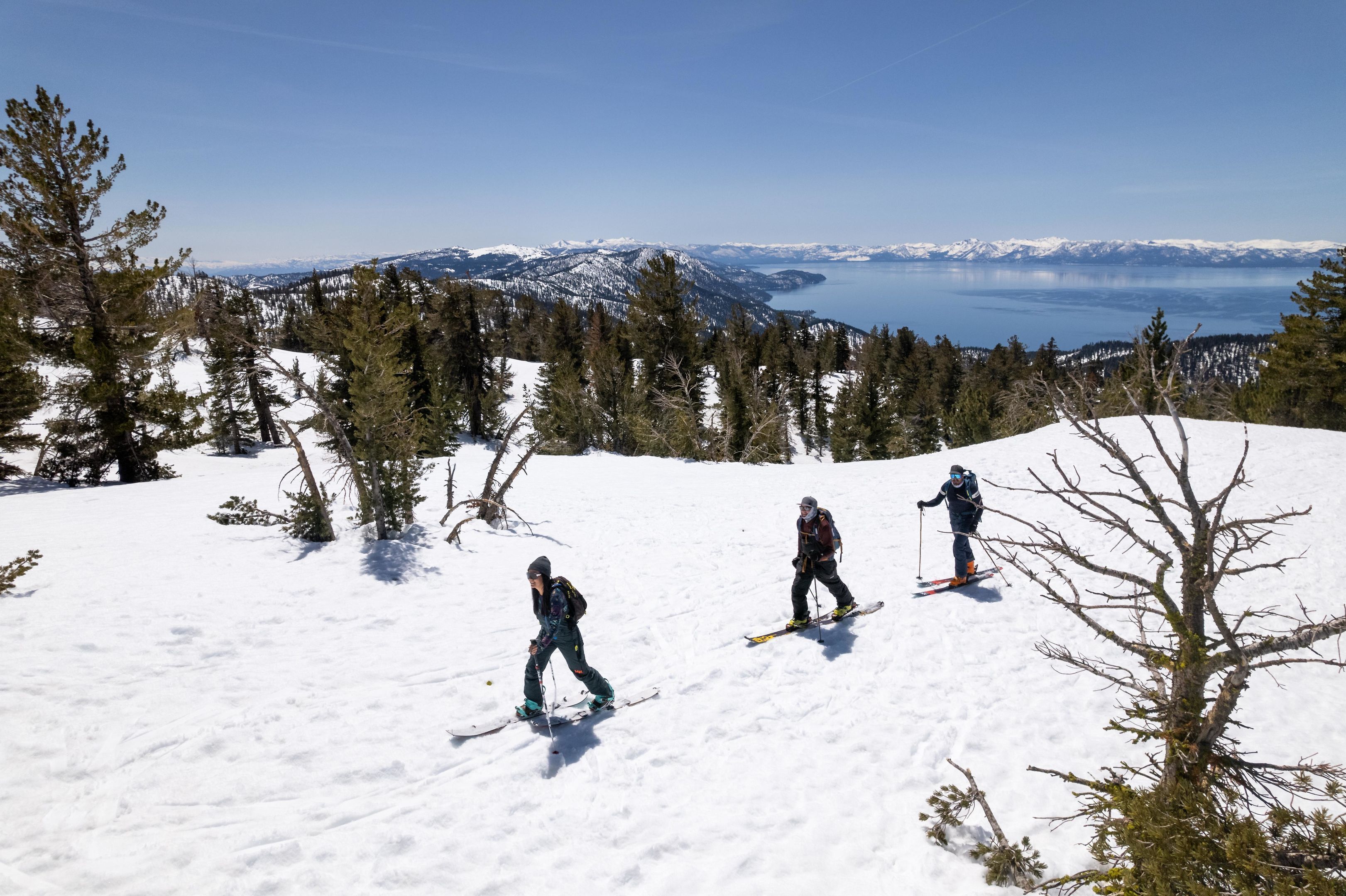 Een besneeerd berglandschap met drie skiërs.