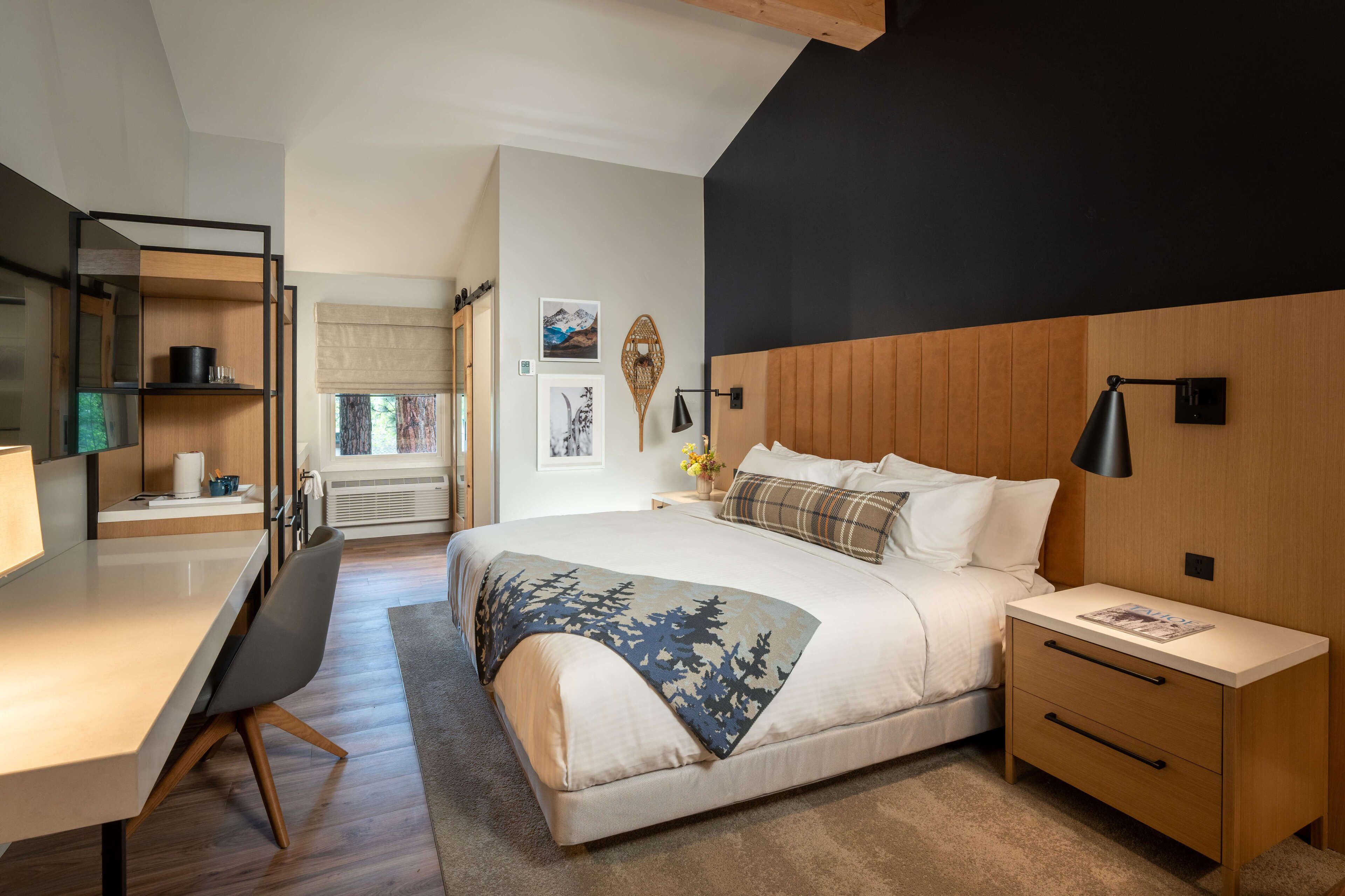 A modern bedroom with a bed, bedside tables, a desk, and a chair.