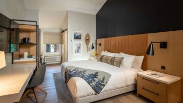 A modern bedroom with a bed, bedside tables, a desk, and a chair.