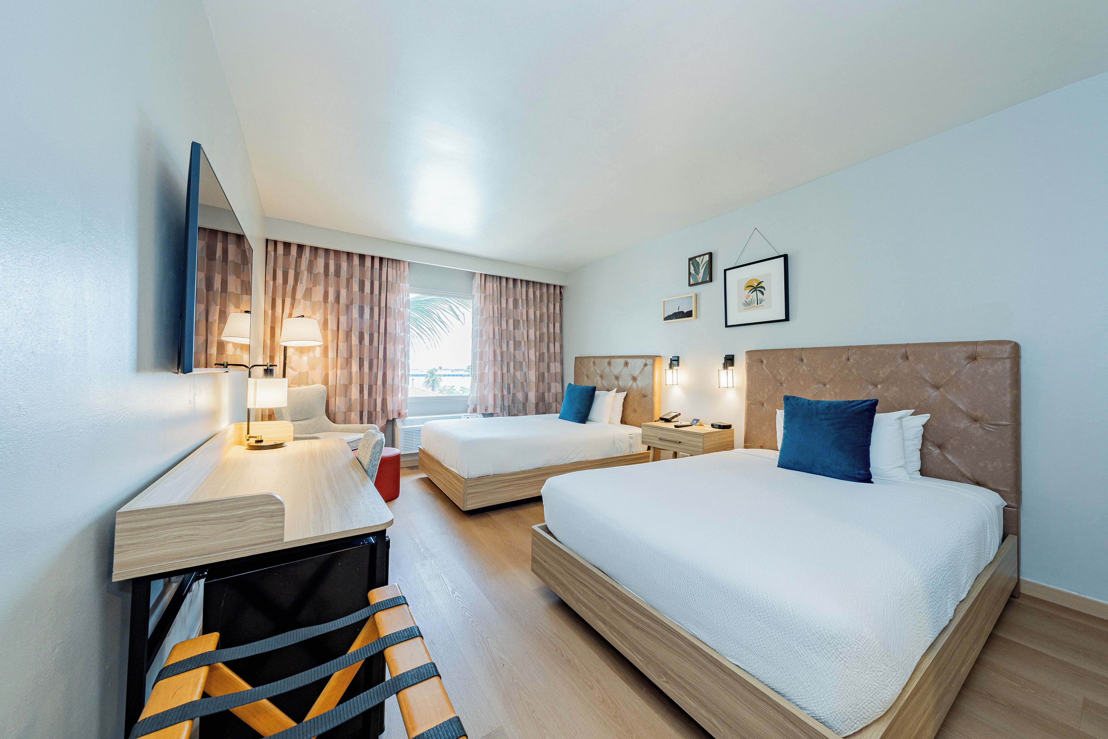 Een hotelkamer met twee bedden, een bureau, een stoel en een televisie.