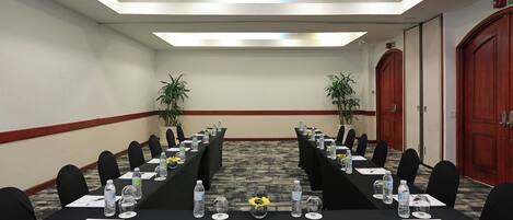 A conference room with a long table, chairs, water bottles, and a vase with sunflowers.