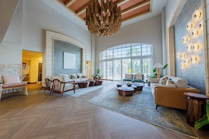 A spacious living area with a high ceiling, large windows, and a variety of seating arrangements. - Four Points by Sheraton Santo Domingo (Boca Chica)