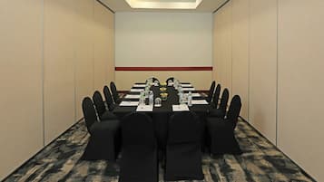 A conference room with a long table, black chairs, and a projector screen.