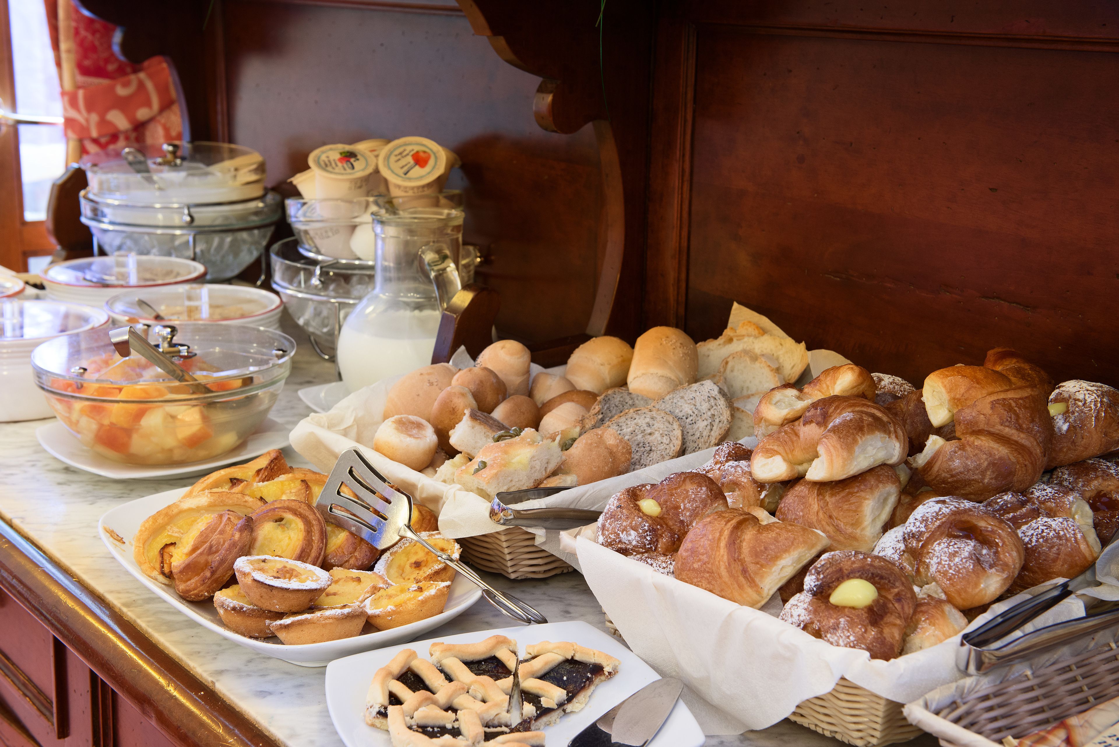 A buffet with various baked goods including pastries, bread, and pies.