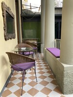 A checkered floor, wicker chairs with purple cushions, a glass table, and a mirror on the wall.