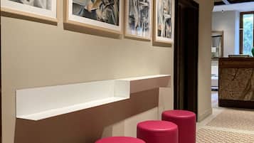 A hallway with abstract art, a white shelf, and red stools.