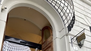 The entrance of Hotel Caravaggio with a wrought iron gate and a glass door.