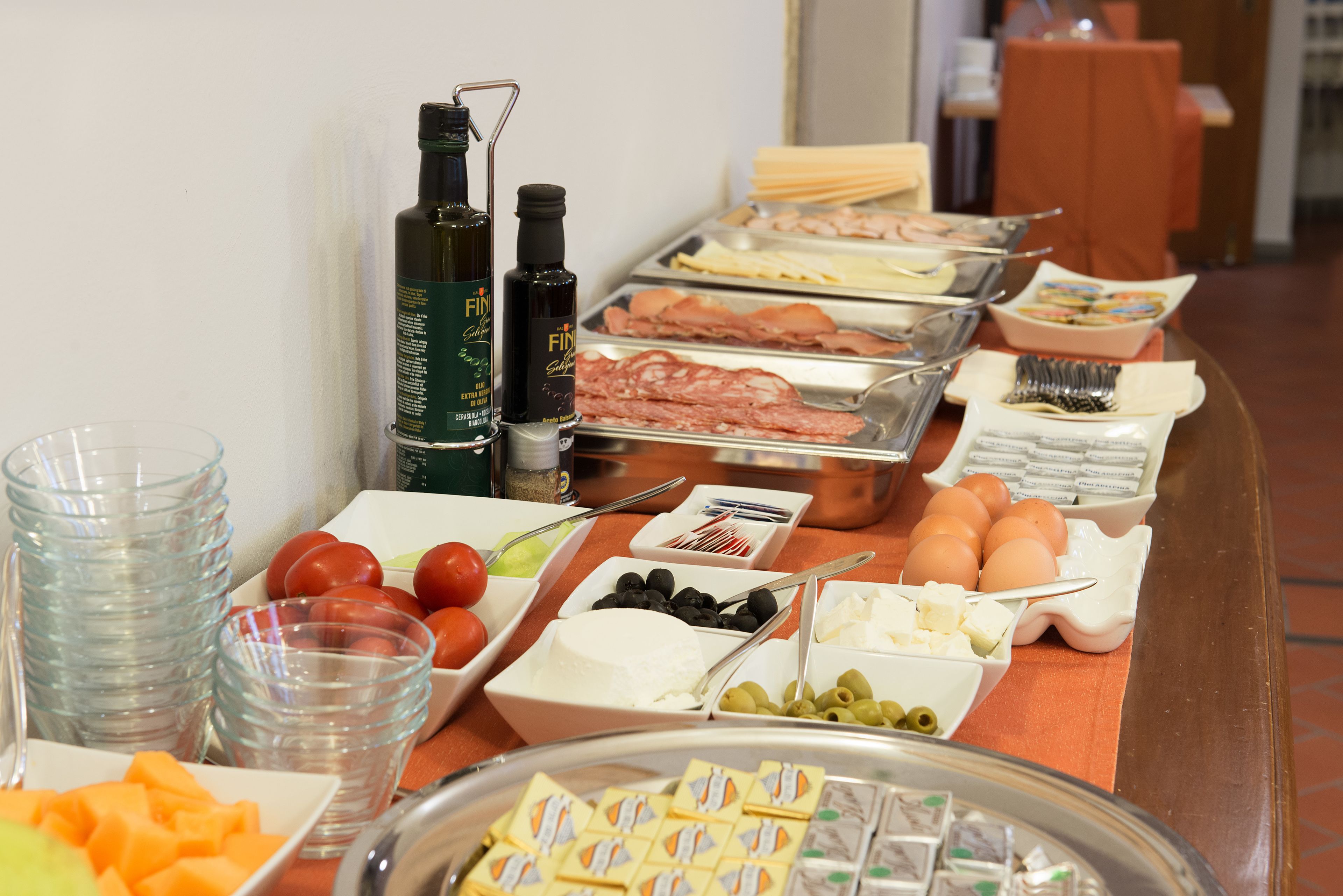 Una mesa de buffet con una variedad de alimentos, incluyendo carnes, quesos, frutas y salsas.