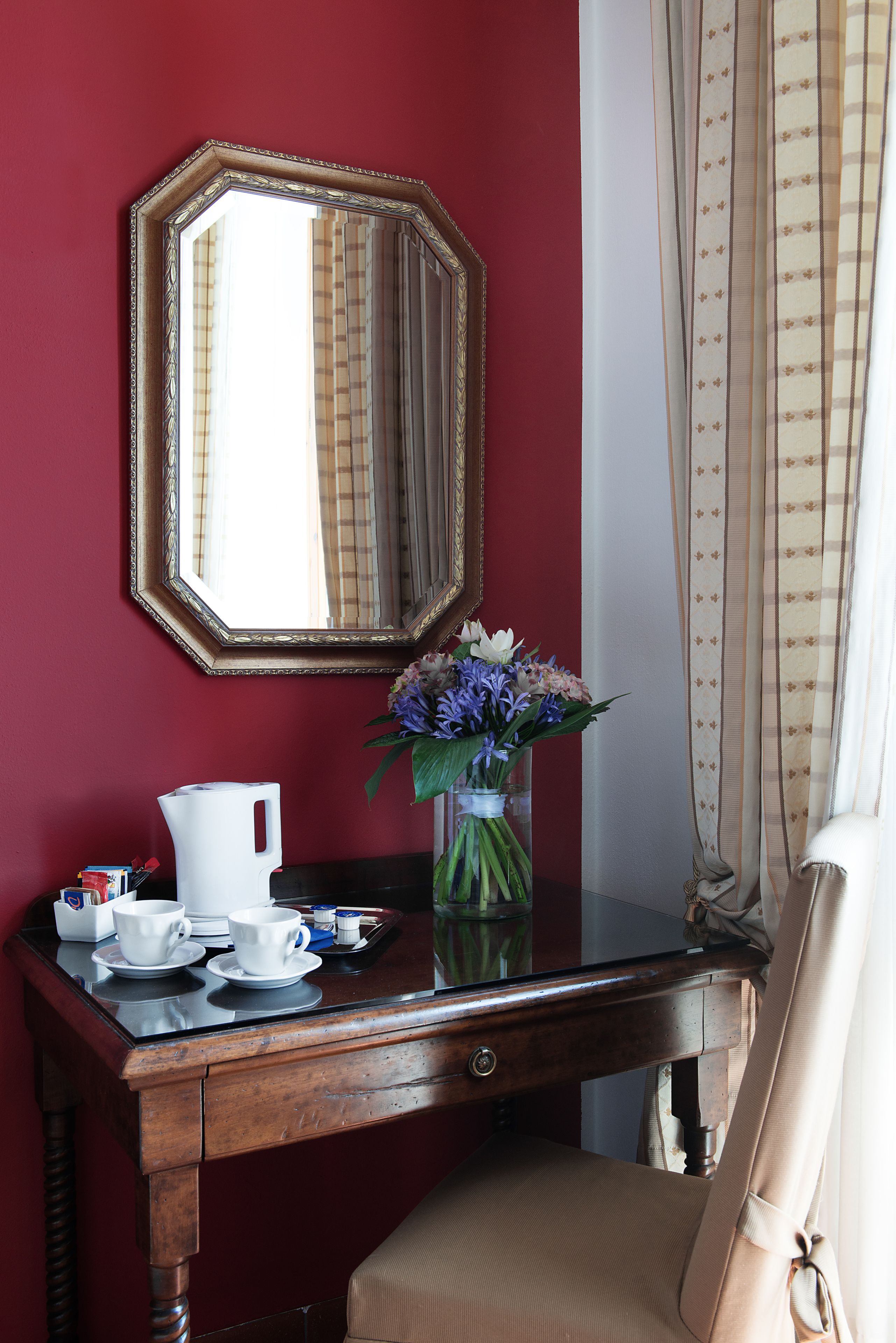 Ein Zimmer mit einem Holztisch, einem Spiegel, einer Vase mit Blumen und einem Stuhl.