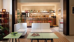 A modern living room with a bar area, featuring a sofa, a coffee table, and a bookshelf.