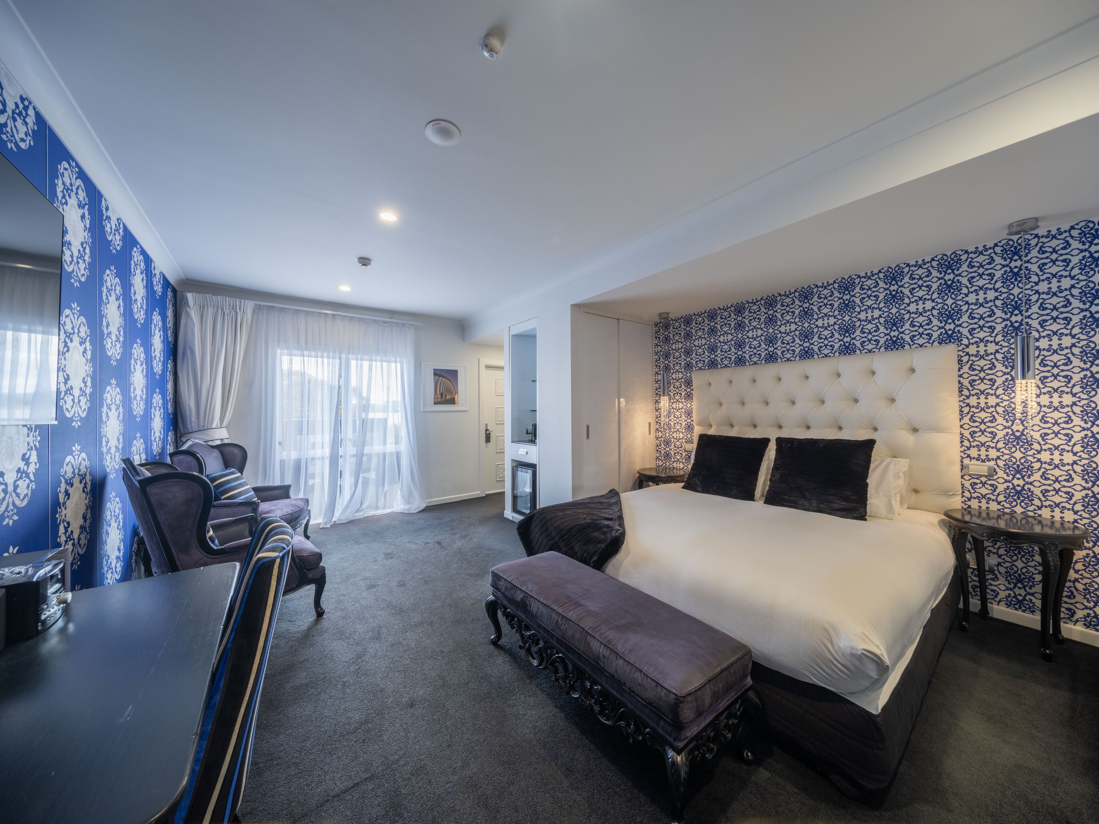 Een moderne hotelkamer met een groot bed, een zithoek met een tafel en stoelen, en een klein bureau.
