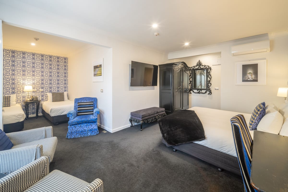 Habitación de hotel con cama, dos mesitas de noche, una silla, televisor, armario y pared con diseño.