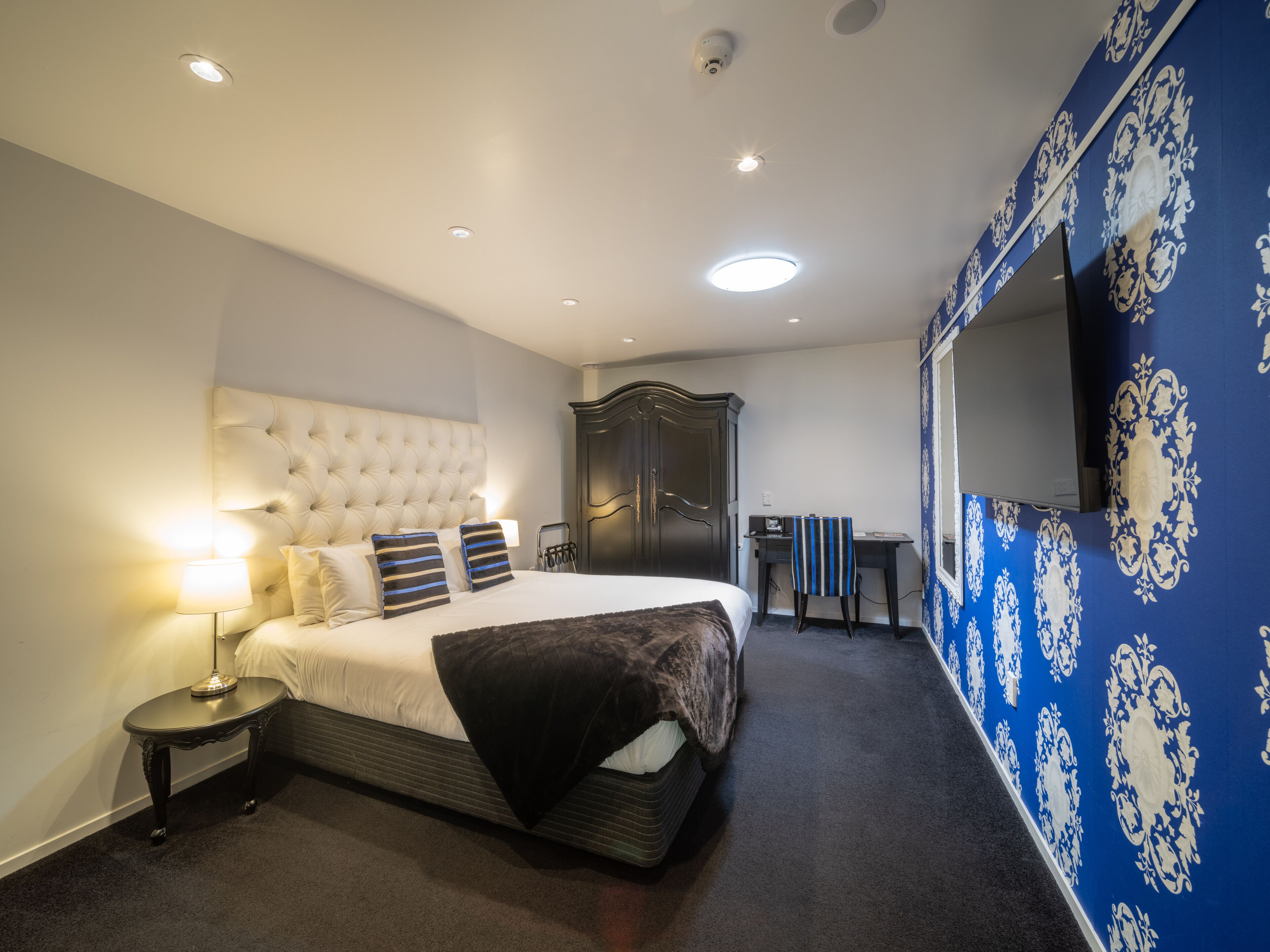 Una habitación de hotel con una cama grande, un escritorio, un armario y un televisor.