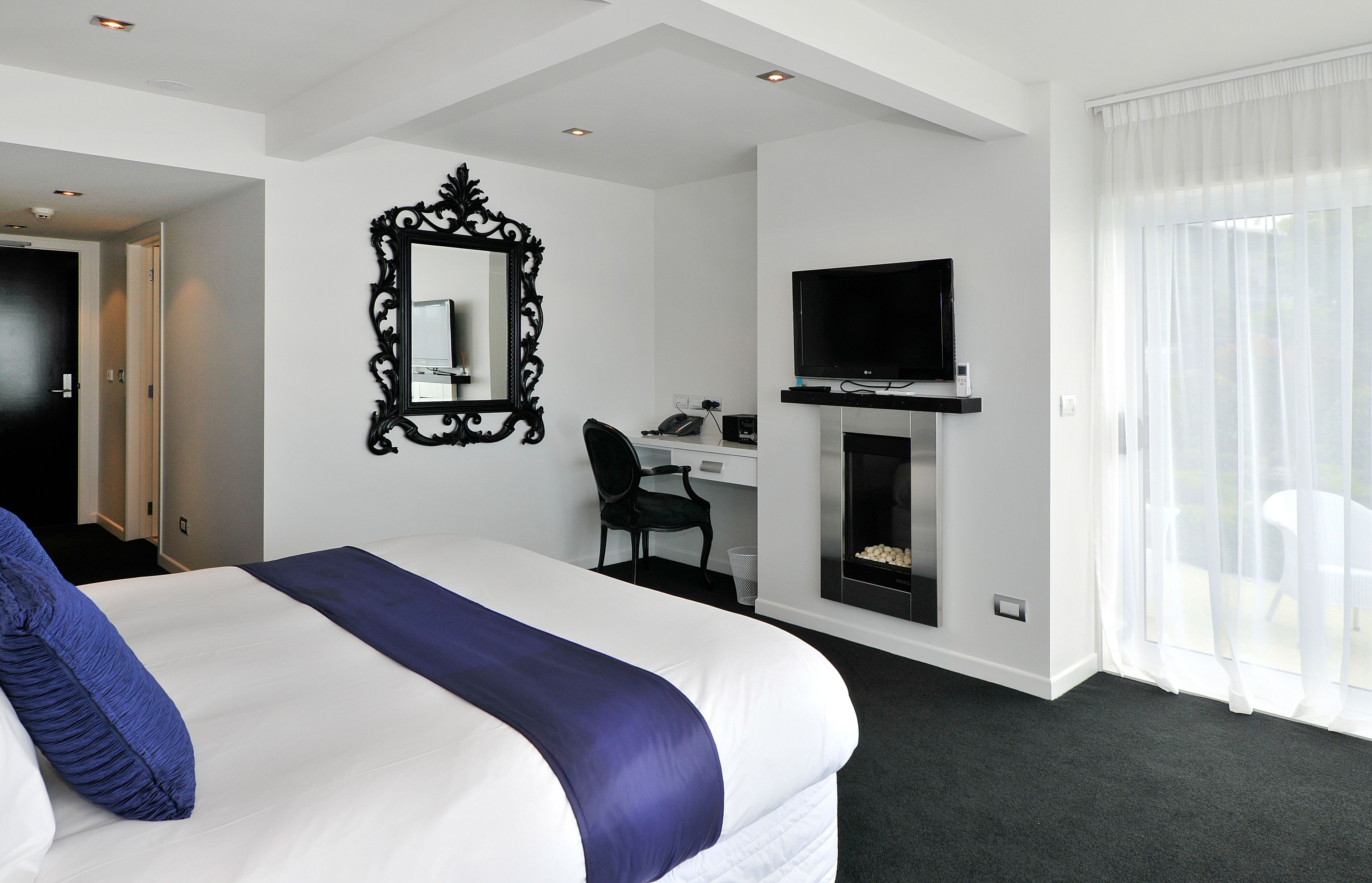 Una habitación de hotel con una cama grande, un escritorio con silla, un televisor y una chimenea.