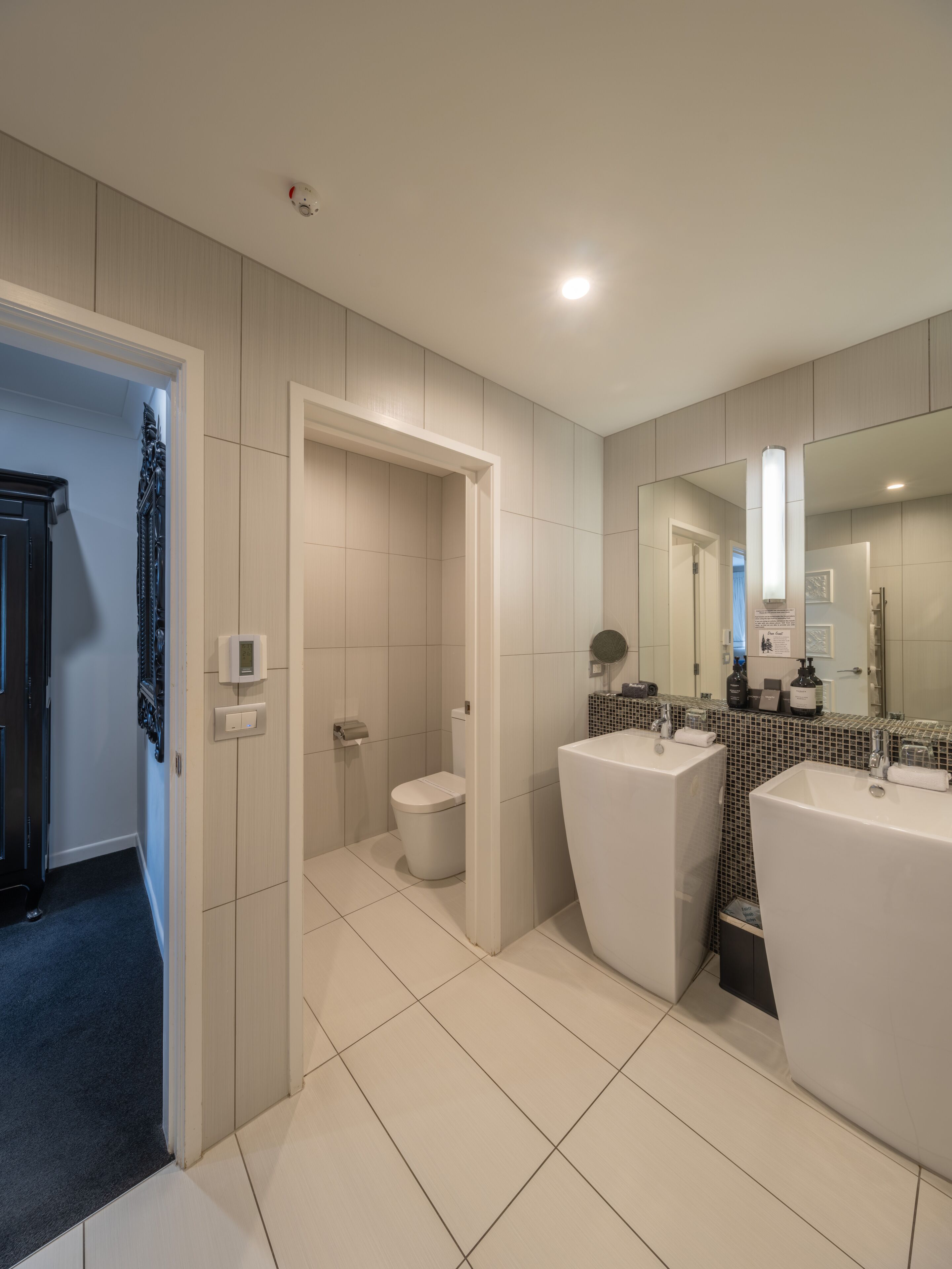 Ein modernes Badezimmer mit zwei Waschbecken, einer Toilette und einer Dusche.