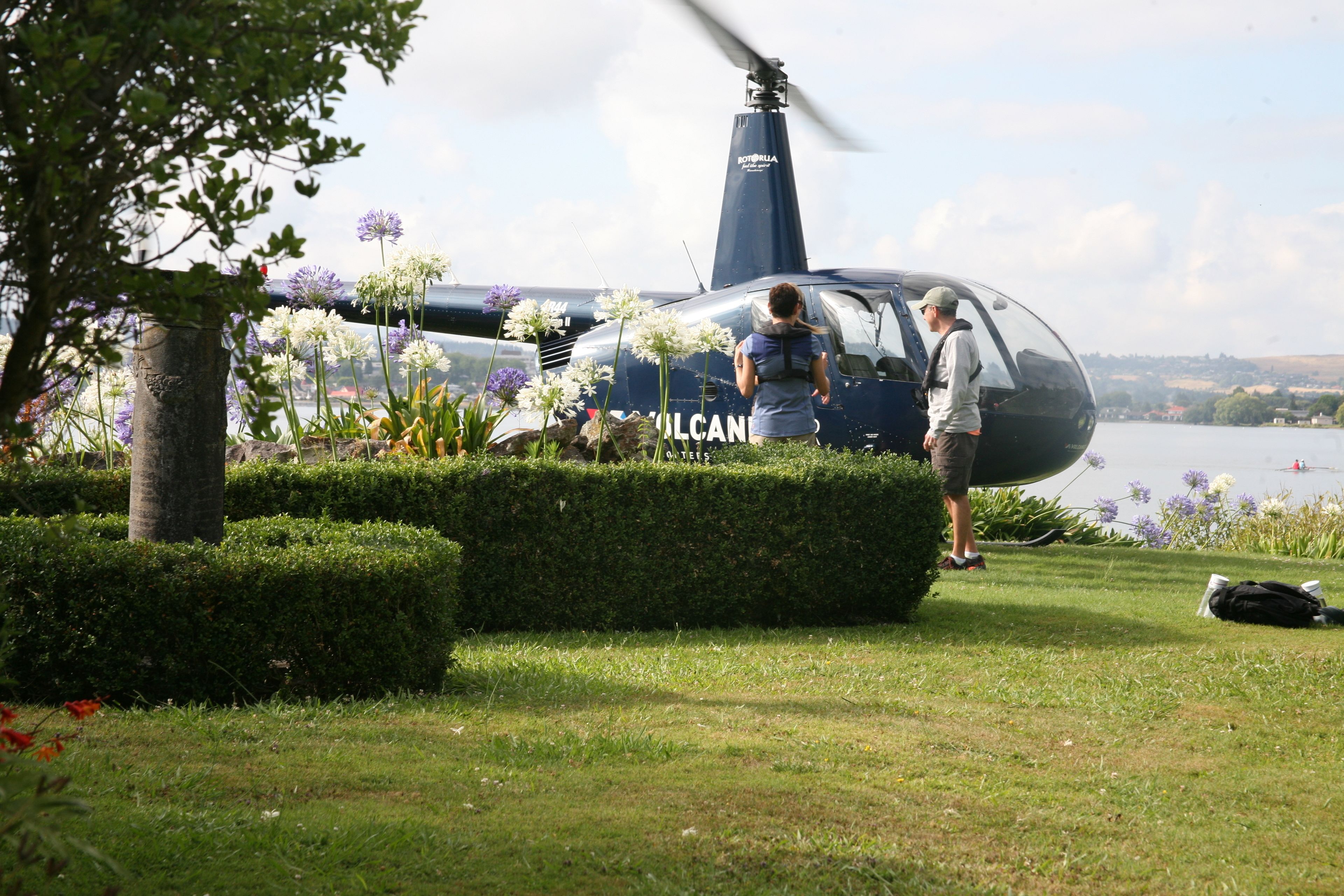 Ein Hubschrauber mit dem Schriftzug "VULCAN" an der Seite, geparkt in der Nähe eines Sees.