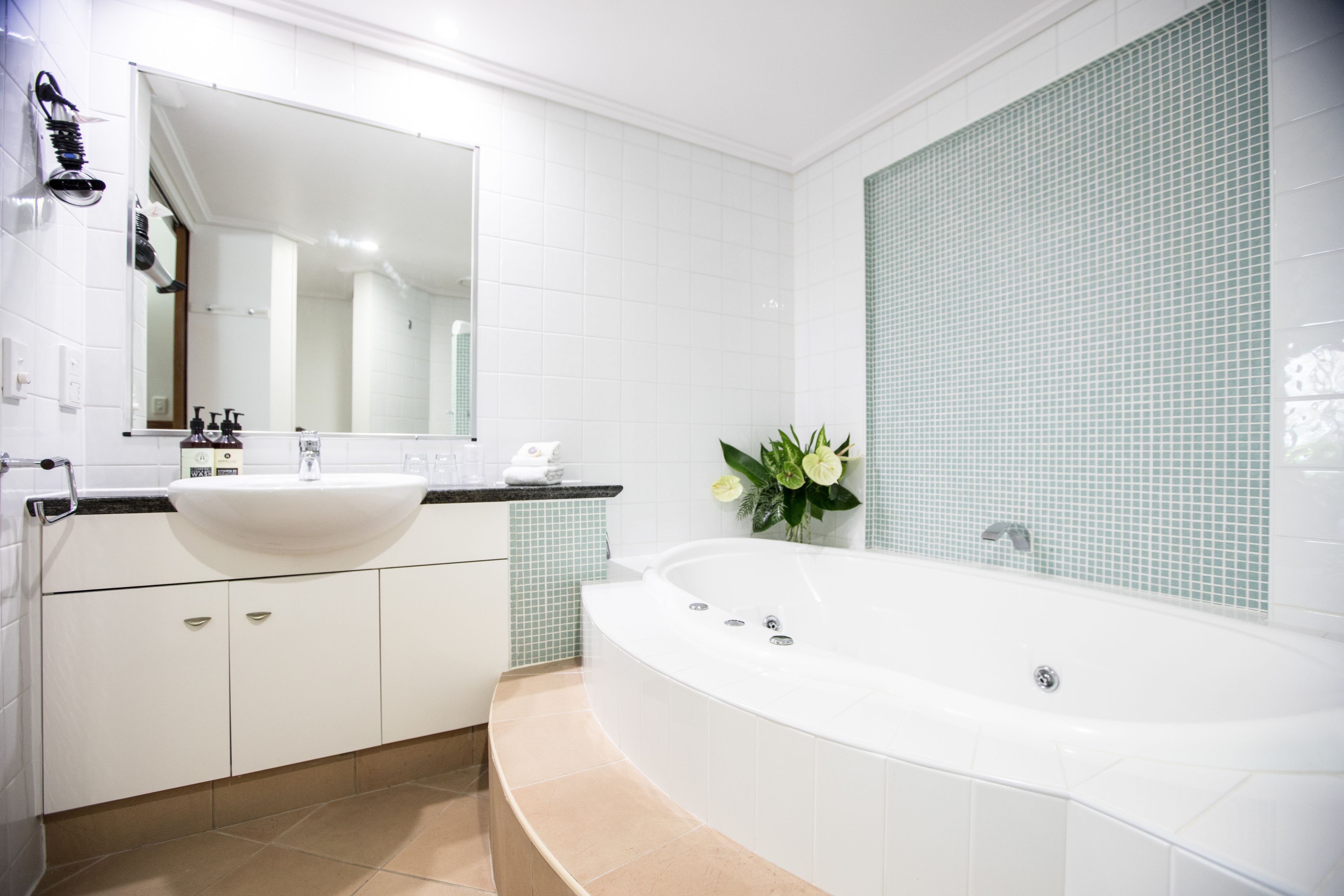 A modern bathroom with a freestanding bathtub, a large mirror, and a white sink.