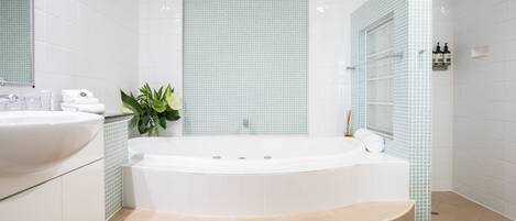 A modern bathroom with a freestanding bathtub, a sink, and a mirror.