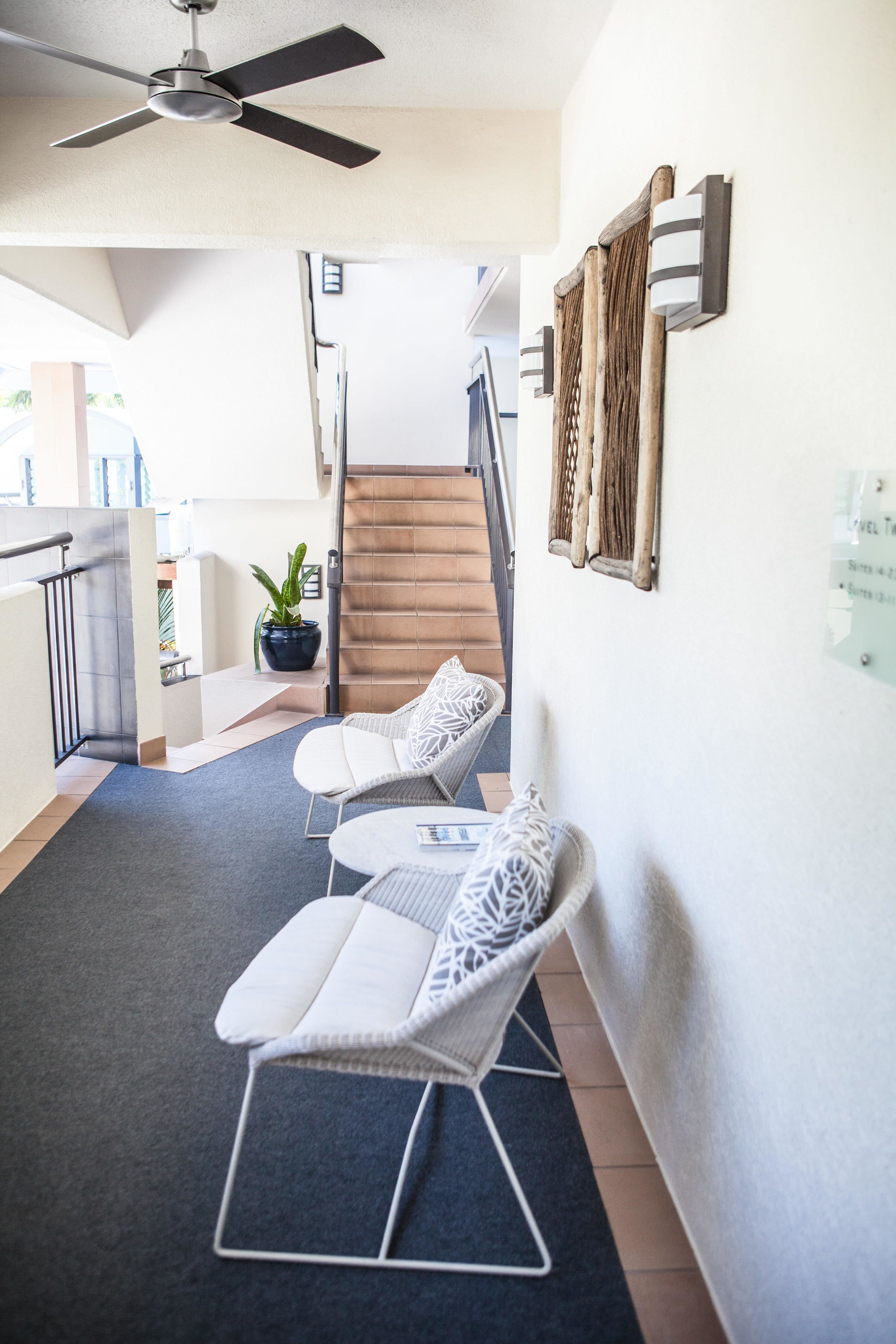 A modern interior with a staircase, white furniture, and a ceiling fan.