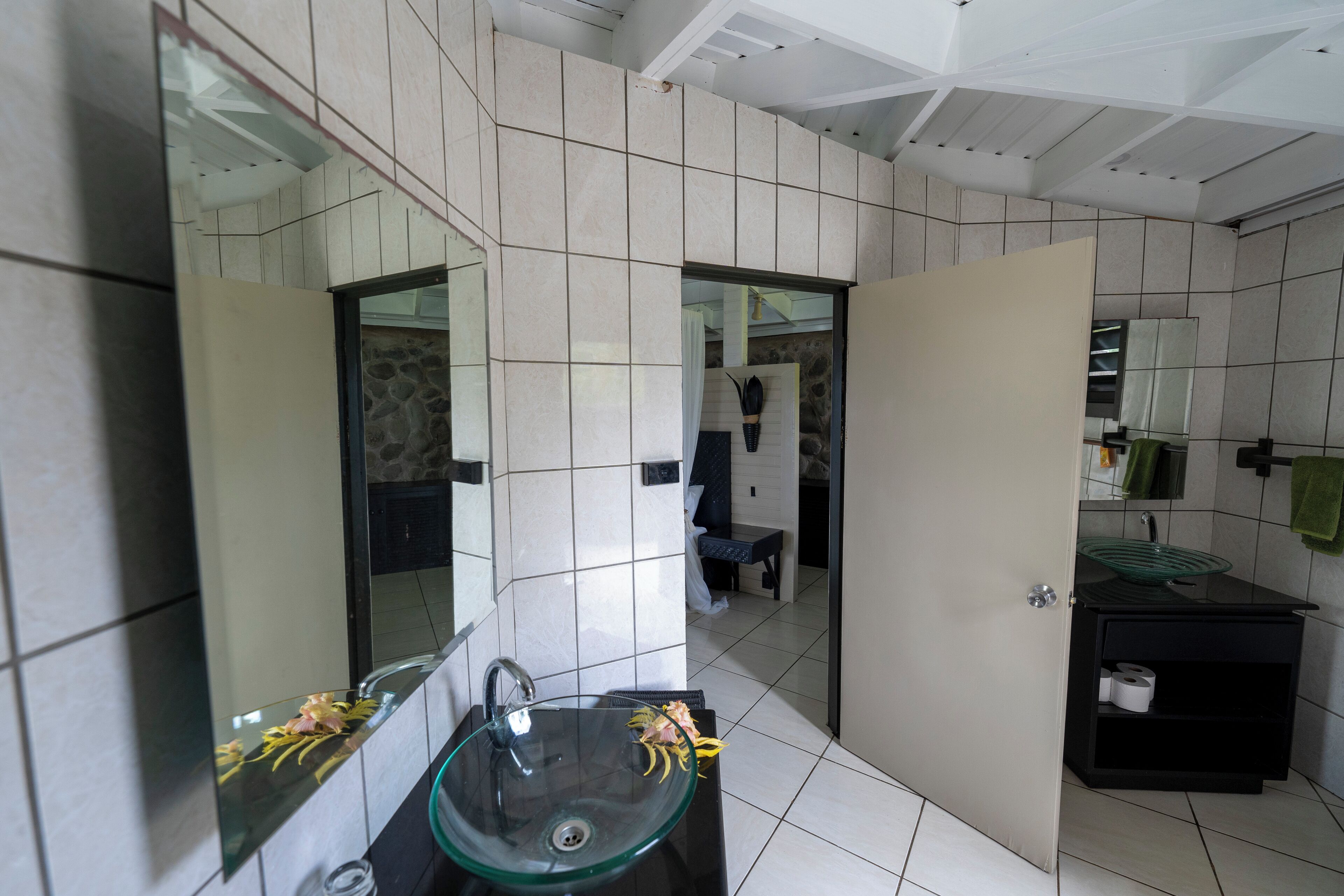 Un baño moderno con un lavabo de vidrio, un espejo y un inodoro.