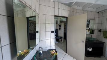 Un baño moderno con un lavabo de vidrio, un espejo y un inodoro.