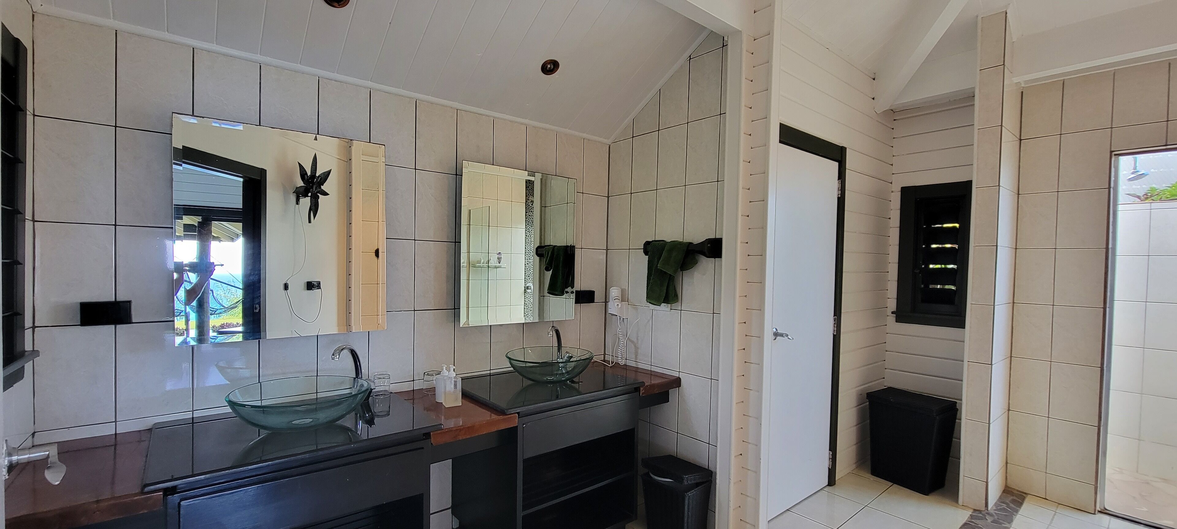 A modern bathroom with two glass sinks, a large mirror, and a tiled wall.