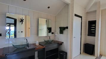 A modern bathroom with two glass sinks, a large mirror, and a tiled wall.