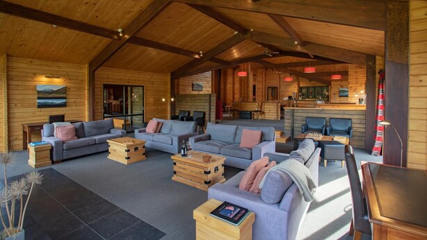 A spacious living area with multiple sofas and a wooden coffee table, a kitchen with a dining area, and a large window providing natural light.