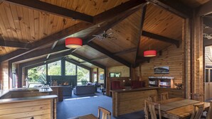 A spacious wooden cabin with a large dining area, kitchen, and seating area.