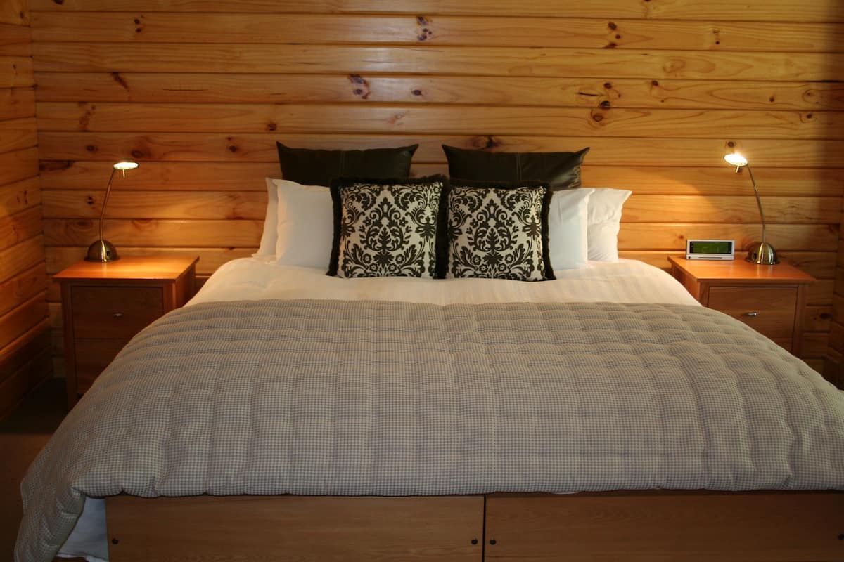 Une chambre à coucher aux murs lambrés, avec un lit, deux tables de chevet et deux lampes.