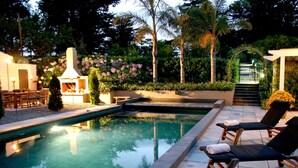 Una piscina con lettini, un'area barbecue e una scala che conduce a una galleria coperta.