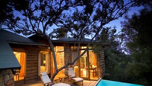 A log cabin with a pool, wooden deck, and outdoor seating area.