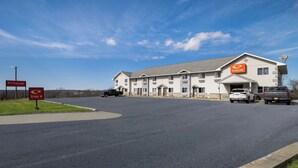 A two-story EconoLodge with a parking lot, a clear sky, and a road leading to the entrance. - Econo Lodge Inn & Suites Canandaigua - Fingers Lake Area (Canandaigua)