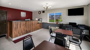 A modern kitchen with a wooden island, a dining area with a table and chairs, a flat-screen TV, and a window with a view of the outdoors. - Econo Lodge Inn & Suites Canandaigua - Fingers Lake Area (Canandaigua)