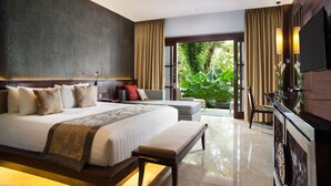A modern hotel room with a large bed, a desk, a TV, and a view of greenery. - Puri Santrian (Denpasar)