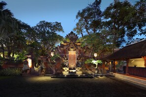A traditional Balinese temple with ornate carvings and a central altar, surrounded by lush tropical vegetation.