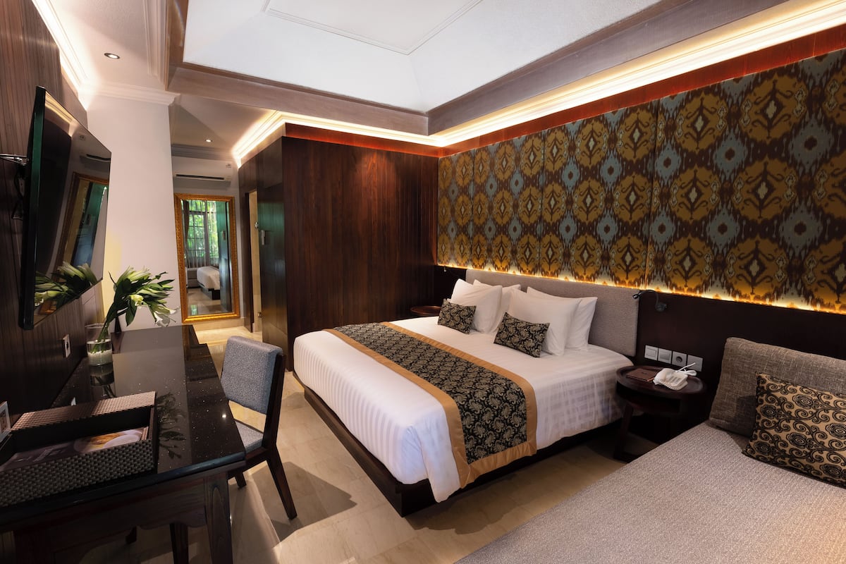 A modern hotel room with a large bed, a desk, and a seating area.