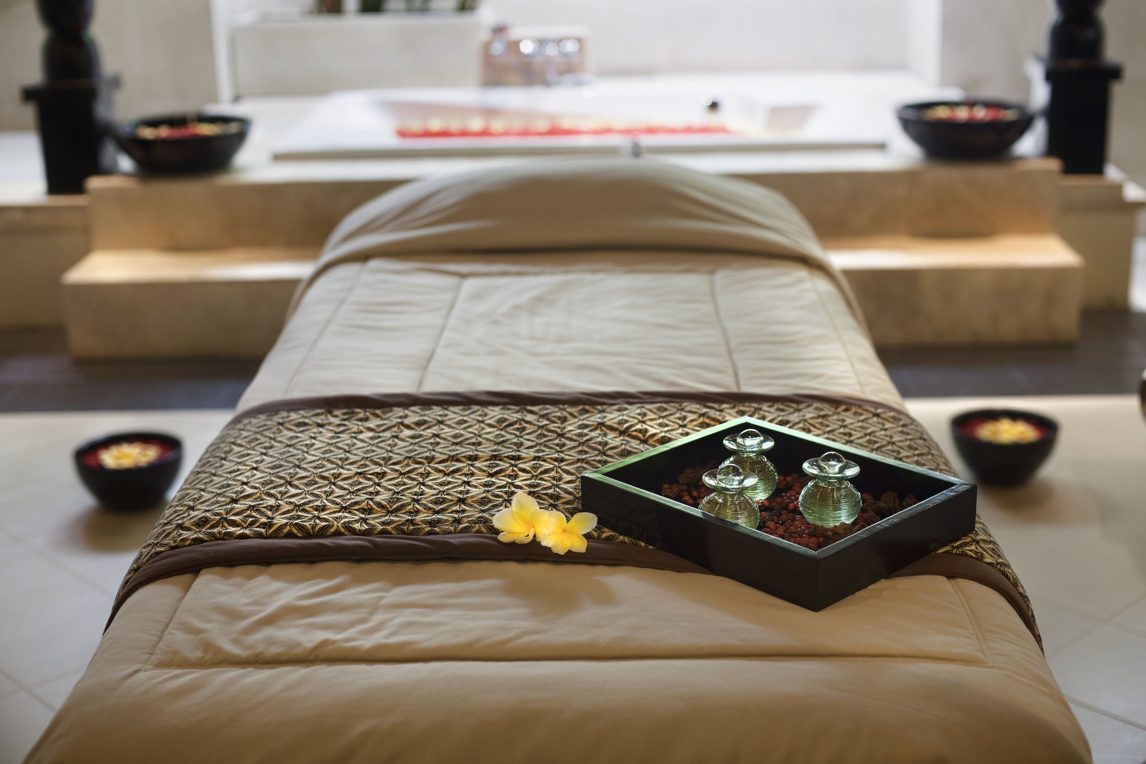 A spa treatment room with a massage table, a tray with candles, and bowls of snacks.
