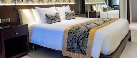 A modern hotel room with a large bed, a bedside table, a mirror, and patterned wallpaper.