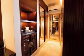 A hallway with a wooden cabinet, a mirror, and a door leading to a room.