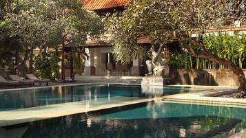 Piscina com espreguiçadeiras e uma estátua de pedra.