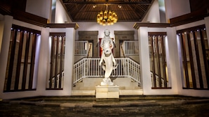 A statue in a lobby with a staircase and a wooden ceiling. - Puri Santrian (Denpasar)