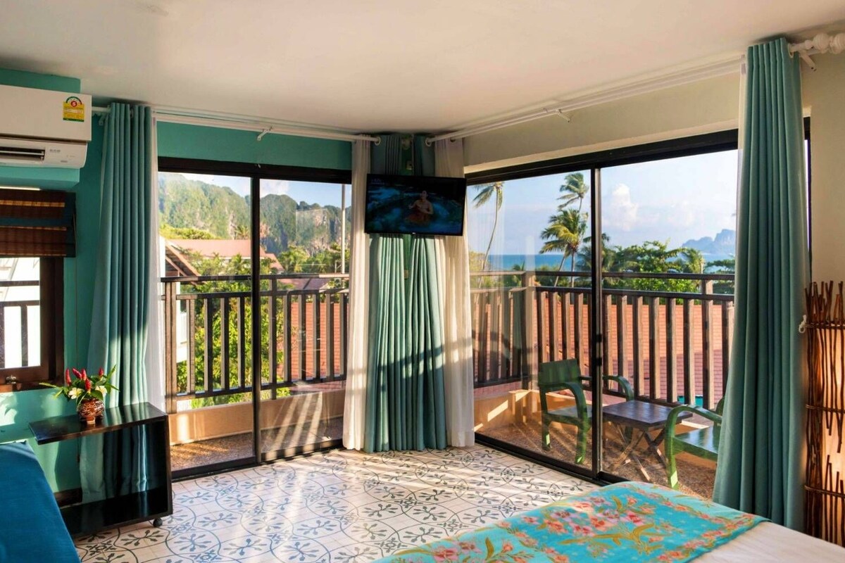 A hotel room with a balcony, a bed, a TV, and a view of the outdoors.