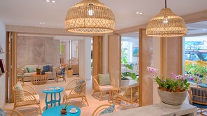 Um lobby moderno de hotel com móveis de vime, uma mesa de centro e uma grande orquídea em vaso.