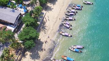 Une plage où plusieurs bateaux sont amarrés le long du rivage, et un bâtiment à toit de chaume situé à proximité.
