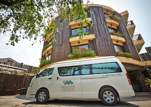 A white van parked in front of a modern building with a unique architectural design, featuring vertical gardens and balconies. - Vacation Village Phra Nang Inn (Krabi)