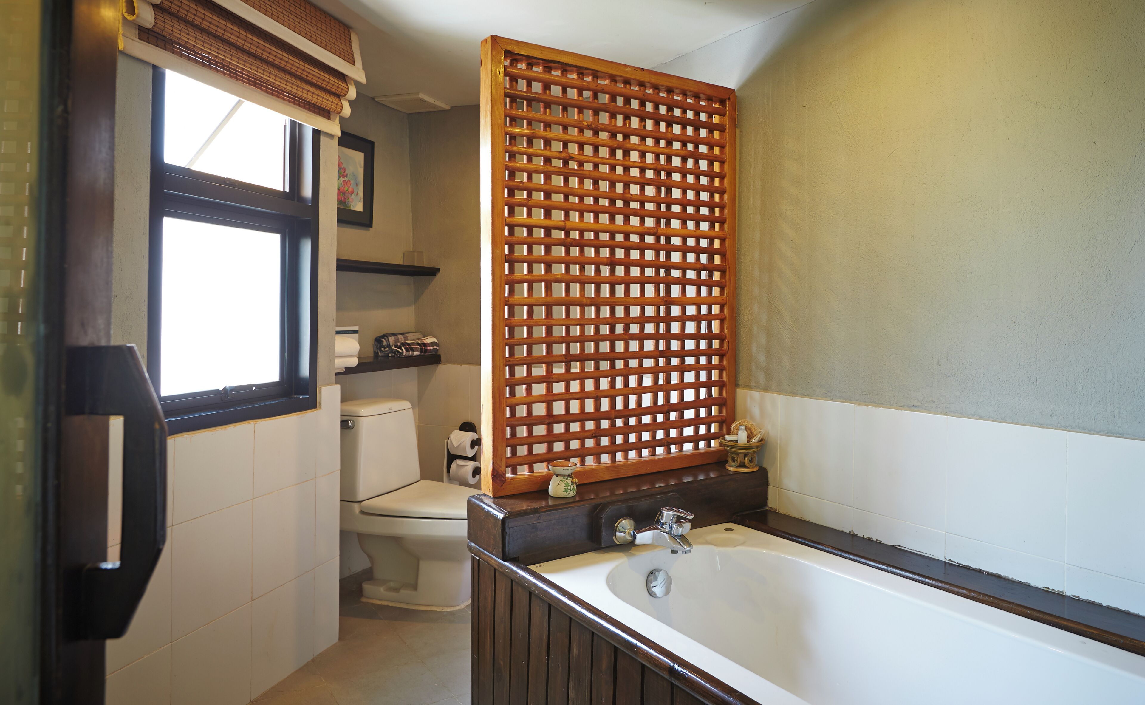 Ein Badezimmer mit Toilette, Waschbecken, einer Holzwand und einem Fenster.